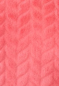 Tejido de color coral rosa con una textura suave y aterciopelada, que presenta un patrón de diamantes en relieve en toda su superficie. Ideal para mantas o plaids acogedores.