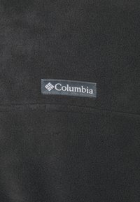 Must mustrõng mustrõhn, mis on rõhutatud Columbia logoga. Pehme tekstuuriga ja siledan pinnaga, nähtavad on minimaalsed õmblusdetailid.