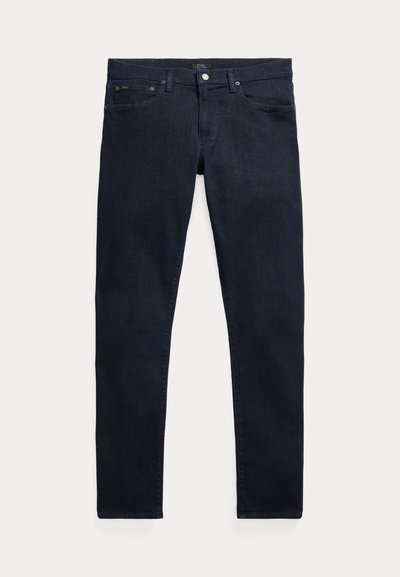 Mørkeblå denimjeans med smal passform. Har fem lommer, glidelås og metallknapp som lukking. Jevn tekstur med minimal falming.