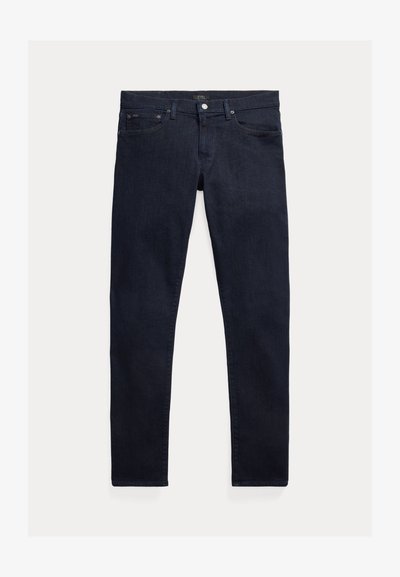 Mørkeblå denimjeans med smal passform. Har fem lommer, glidelås og metallknapp som lukking. Jevn tekstur med minimal falming.