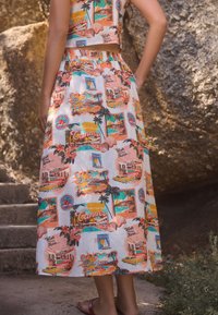 Gonna lunga in cotone floreale con stampa colorata "Saluti da Cannes", con palme e auto d'epoca. Vita elasticizzata, lunghezza al polpaccio.