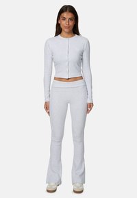 Gray long-sleeve cropped top with button closure, paired with gray flared leggings. Both in soft, textured fabric. Casual athletic wear.