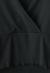 Crni rebrasti materijal top s dizajnom omotača, koji ima nabran rub i glatku teksturu. Nema vidljivih uzoraka ili metalnih detalja.