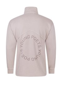 Béžový dlouhý pulovr s dlouhým rukávem a vysokým límcem. Na zádech má tmavě béžový kruhový text "YOUNG POETS". Měkká textura.