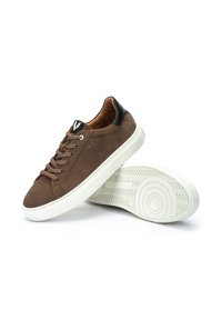 Baskets en daim marron avec une semelle en caoutchouc blanc, dotées de lacets marron, d'une accentuation noire à l'arrière du talon et d'un motif texturé sur la semelle extérieure blanche.