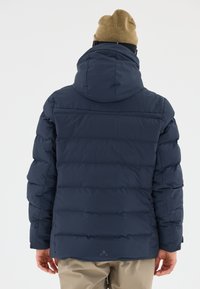 Dunkelblauer Pufferjacke mit Kapuze, die über gesteppten Bereiche und ein dezentes Logo nahe dem Saum verfügt. Hergestellt aus einem glatten, leichten Material.