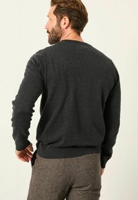 Grau gestrickter Pullover mit langen Ärmeln, Rundhalsausschnitt und geripptem Saum. Die Textur wirkt weich und gemütlich, ideal für legere Outfits.