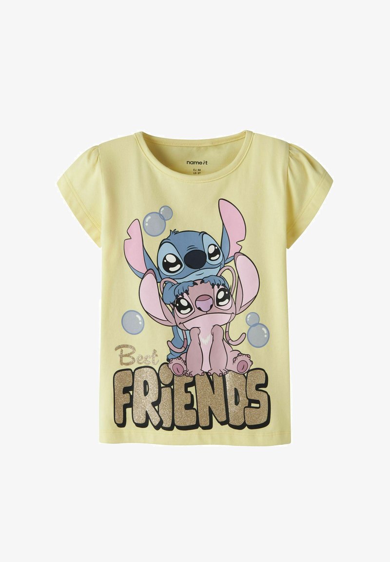 T-shirt jaune pour enfants avec les personnages de dessin animé Stitch et Angel s'enlaçant au-dessus du texte pailleté « Meilleurs AMIS » et des bulles flottantes.