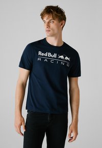 Marineblauw katoenen t-shirt met korte mouwen, voorzien van een wit 'Red Bull Racing' logo en een graphic van twee stieren, ronde hals en rechte pasvorm.
