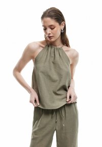 Olijfgroene haltertop van structuurstof, met een geplooide halslijn en een losse pasvorm. Gepaard met bijpassende relaxte broek.