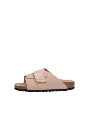 Sandal beige à enfiler avec une large bride, fermeture Velcro, semelle en liège et semelle en caoutchouc noir. Texture lisse avec des accents subtils.