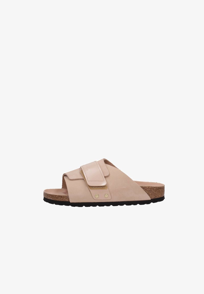 Sandalo beige scivolato con una larga fascia, chiusura in velcro, soletta in sughero e suola in gomma nera. Texture liscia con accenti delicati.