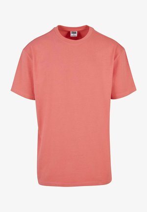 Koralowa różowa koszulka z krótkim rękawem wykonana z bawełny; posiada klasyczny okrągły dekolt oraz prosty krój bez dodatkowych wzorów czy akcentów.