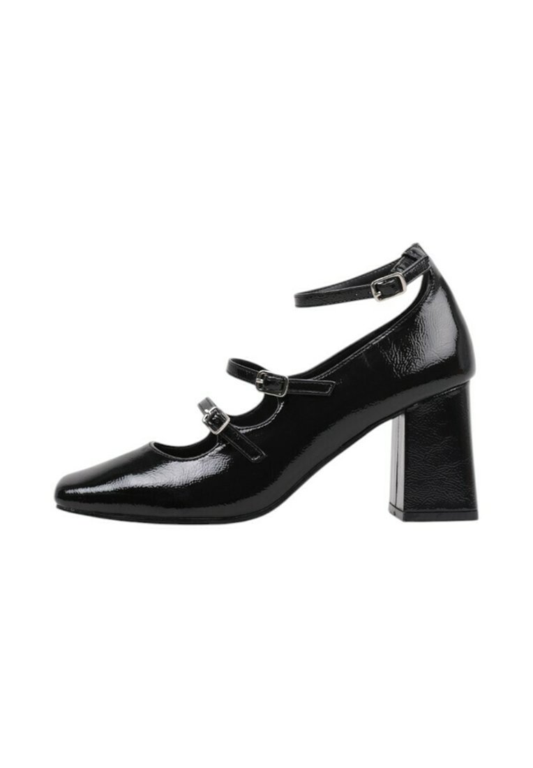 Tacones altos de charol negro con punta afilada, que cuentan con dos correas ajustables en el tobillo y un tacón grueso. Textura suave y acabado brillante.