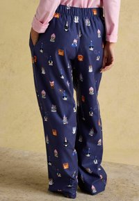 Navigační pyžamové kalhoty s elastickým pasem, zdobené opakujícím se vzorem barevných kreslených zvířátek a párty kloboučků. Kapsy na každé straně.