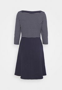 Marinblå klänning med vita horisontella ränder, trekvartsärmar och en utställd kjol. Slät textur med en åtsittande bodice och avslappnad nederdel.