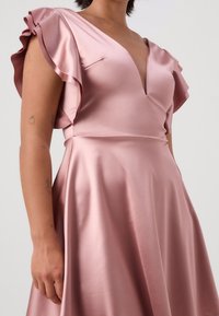 Pink satin dress featuring a deep V-neck and ruffled short sleeves, with a smooth texture and a flowing design that emphasizes drape.