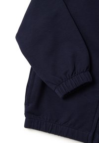 Sudadera azul marino con puños de canalé, textura suave y bolsillos laterales con cremallera. Diseño sencillo con dobladillo elástico.