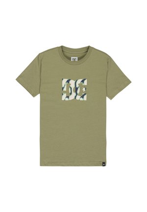 T-shirt vert olive à manches courtes avec un grand logo DC en motif camouflage blanc et vert centré sur la poitrine.