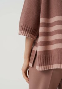 Neulepusero hillityssä ruusunsävyssä, jossa vaaleanpunaiset vaakaraitarit. Varustettu resoreilla hihansuissa ja helmassa. Sivuhalkiot korostavat rentoa siluettia.