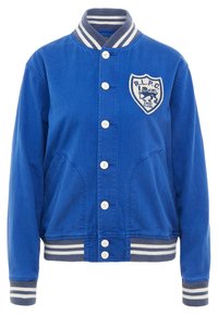 Modrá univerzitní bunda s bílými knoflíky, pruhovaným ribbovaným límcem a manžetami, předními kapsami a nášivkou se lvem, na které je nápis "R.L.P.C. První třída."