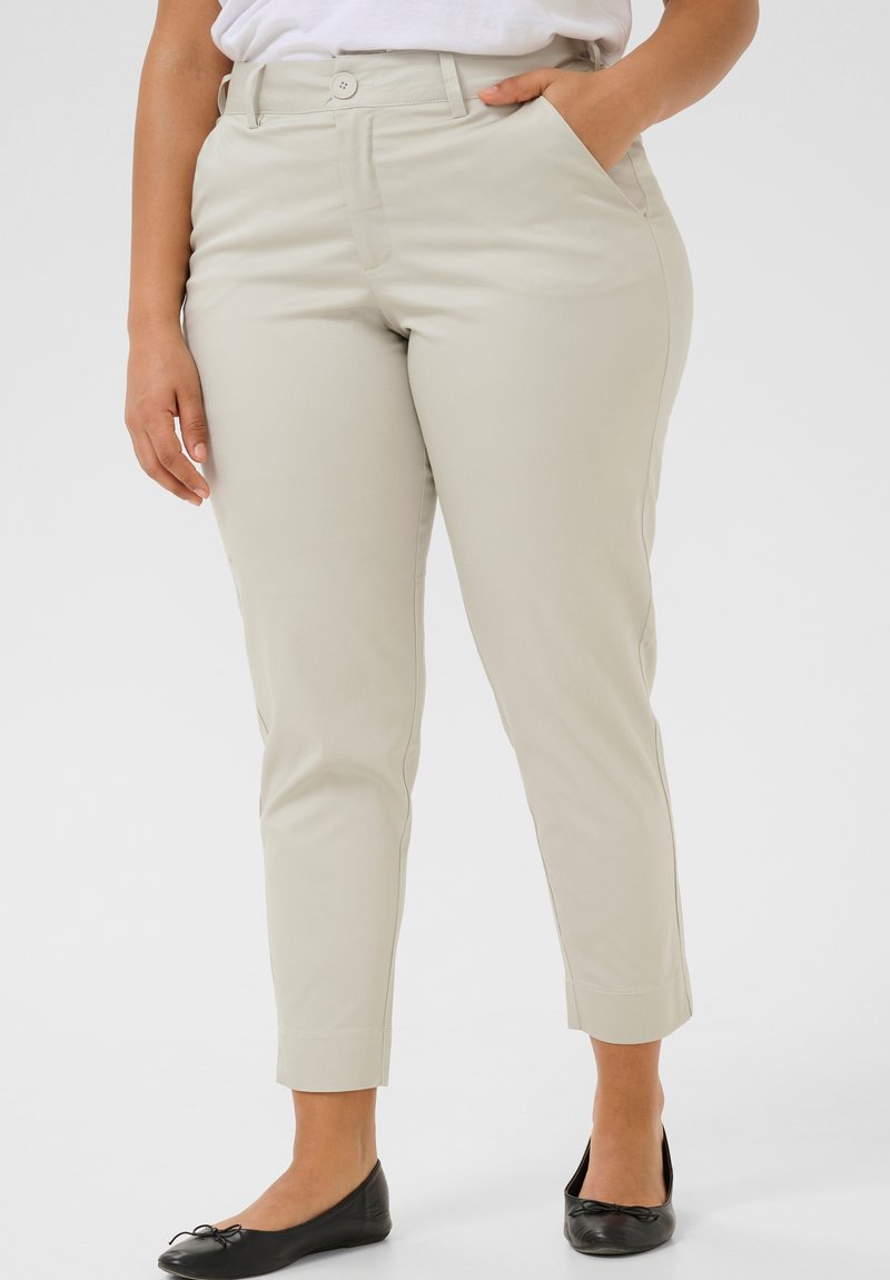 Pantaloni beige su misura con una texture liscia e una vestibilità affusolata. Presentano tasche laterali e una chiusura a singolo bottone in vita.