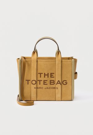 Τσάντα tote από σουέτ σε καμηλό απόχρωση Marc Jacobs με δύο χερούλια στην κορυφή, αποσπώμενο λουρί ώμου και έντονο κείμενο "THE TOTE BAG" στο μπροστινό μέρος.