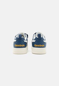 Modré kožené tenisky s bielymi akcentmi, so štruktúrovaným povrchom a žltým logom "Reebok" na päte. Gumená podrážka.