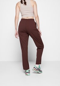 Bruna, löst sittande byxor i mjukt material. Har en elastisk midja och sidofickor. Bärs med färgglada sneakers.