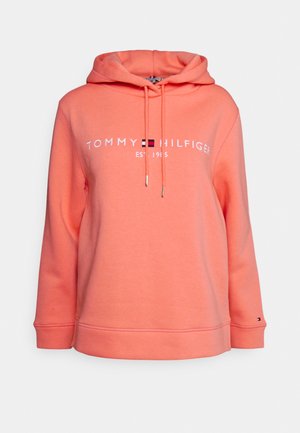 Coral pink hoodie with front drawstrings, long sleeves, and "Tommy Hilfiger Est. 1985" logo and flag centered on chest.