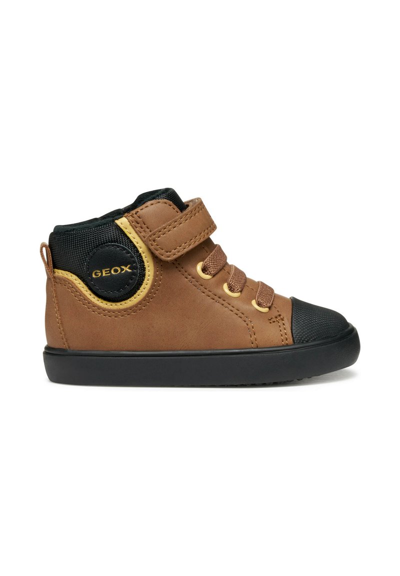 Bottine marron avec un embout noir, dotée d'une sangle velcro et de lacets. Détails jaunes et panneau en maille noire sur le côté.