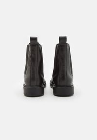 Svarta läderankelstövlar med elastiska sidopaneler, slät yta, rund tå och platt gummisula, med en dragflik baktill.