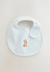 Bavoir blanc pour bébé avec des pois roses, fermeture à pression, et un lapin marron brodé tenant une fleur rose au centre en bas.