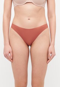 Bikini donji dio visoki struk, boje rđe, s glatkim, rastezljivim materijalom i dizajnom s minimalnim prekrivanjem, koji prikazuje čiste linije i bešavnu završnicu.
