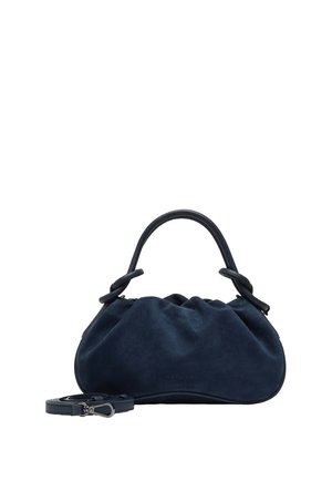 Kleine marineblaue Wildleder-Handtasche mit kurzem rundem Griff und abnehmbarem Schulterriemen neben ihr auf weißem Hintergrund.