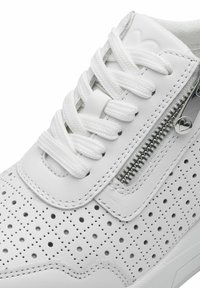 Weißer Sneaker aus perforiertem Leder, flachen weißen Schnürsenkeln und einem seitlichen Reißverschluss mit metallischen Elementen. Glatte Textur und runde Zehenpartie.