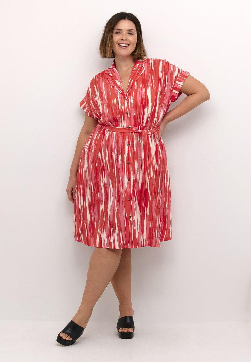 Rood en wit gestreepte blousejurk met korte mouwen, een ceintuur in de taille en een zwierige rok. Gecombineerd met zwarte, open-toe plateau schoenen.