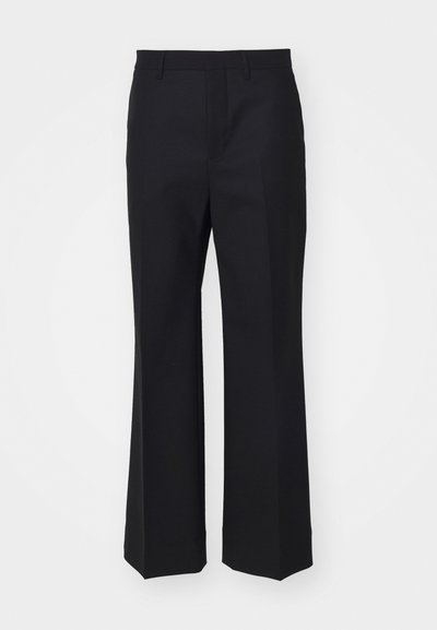 Pantalones negros a medida hechos de una tela suave; diseño de pierna ancha con frente plano y sin bolsillos visibles ni adornos.