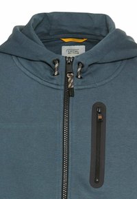 Blauwe hoodie met een rits, voorzien van een voorzak en trekkoorden aan de capuchon. Etiket met "camel active." Zacht stofoppervlak.