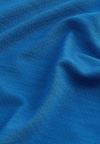 Primo piano di tessuto blu lavorato a maglia che mostra una trama fine e pieghe morbide.