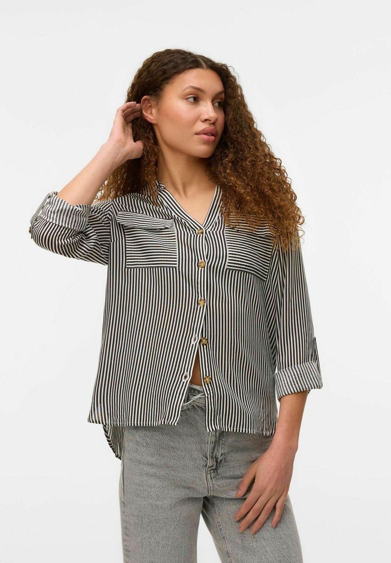 Stripet button-up skjorte med sort-hvide lodrette striber, to brystlommer og optrukne ærmer. Let stof, afslappet pasform.