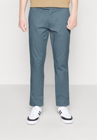 Ljusa blå chinos med slim fit, tillverkade av mjukt bomullstyg, med dragkedja, bälteshällor och sidofickor. Matchas med vita sneakers.