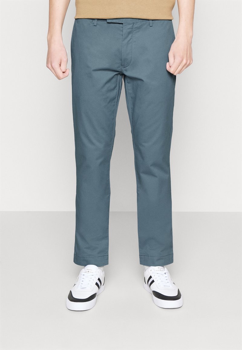 Ljusa blå chinos med slim fit, tillverkade av mjukt bomullstyg, med dragkedja, bälteshällor och sidofickor. Matchas med vita sneakers.