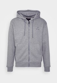Felpa grigia con zip, dotata di cappuccio regolabile con cordino, tasche frontali e logo Jumpman ricamato sul petto. Realizzata in un tessuto morbido e caratteristico.