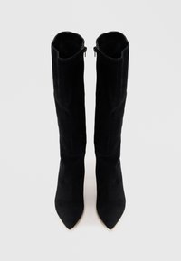Bottes en suède noires au-dessus du genou avec un bout pointu et une silhouette élancée, dotées d'une fermeture éclair à l'arrière pour un enfilage facile.