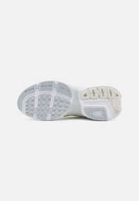 White athletic shoe sole with textured rubber in light gray and white, featuring grooves and patterns for traction and flexibility.