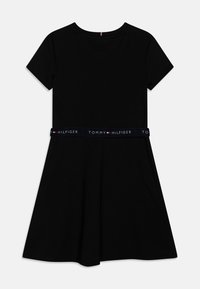 Černé šaty s krátkým rukávem, rozšířenou sukní a námořnickým elastickým pasem s bílým logem "TOMMY HILFIGER". Hladký bavlněný materiál.