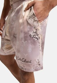 Korte, mønstrede shorts i dæmpede brune og beige nuancer, med elastisk talje og sidelommer. Mærkets logo nær kanten.