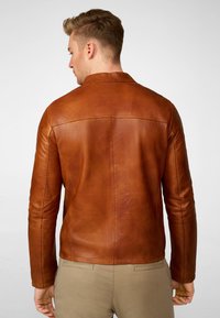 Brun læderjakke med en glat tekstur, slim fit og en båndkrave, der har sømdetaljer på ryggen og lange ærmer.