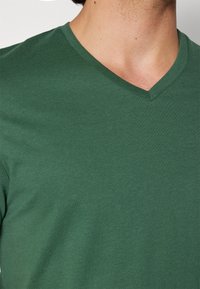 Green cotton V-neck T-shirt, featuring a smooth texture, a fitted shape, and a clean neckline. No distinguishable patterns or accents visible.